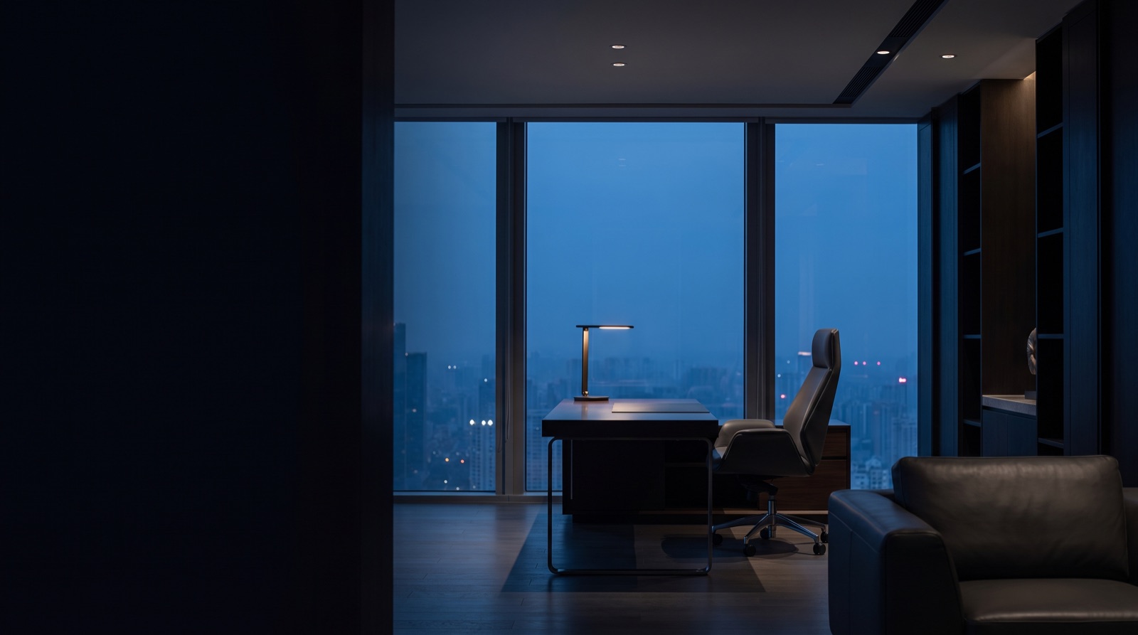 Quiet executive workspace at dusk, twilight city beyond the glass